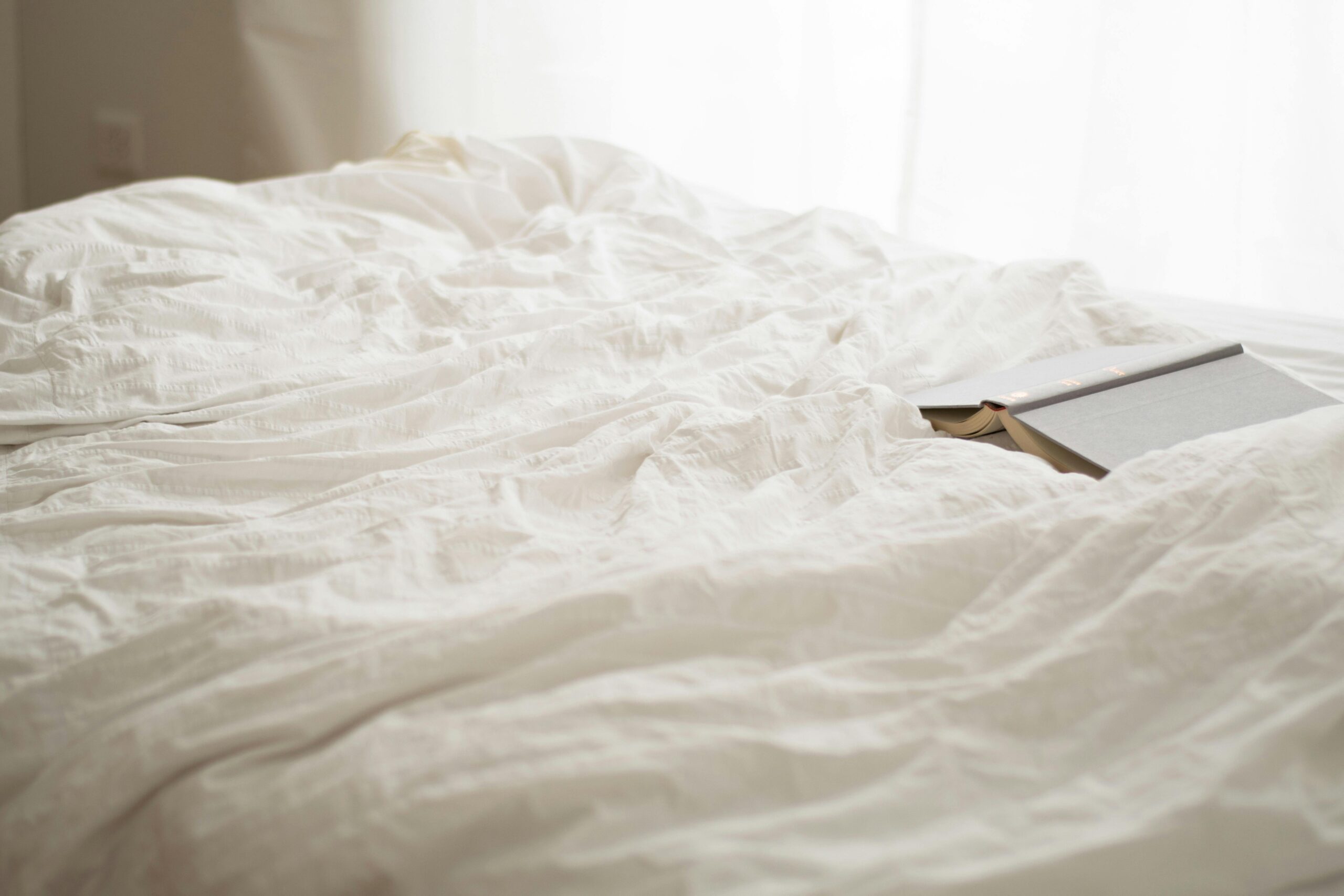 "Luxurious white cotton bedsheet neatly spread on a hotel bed"